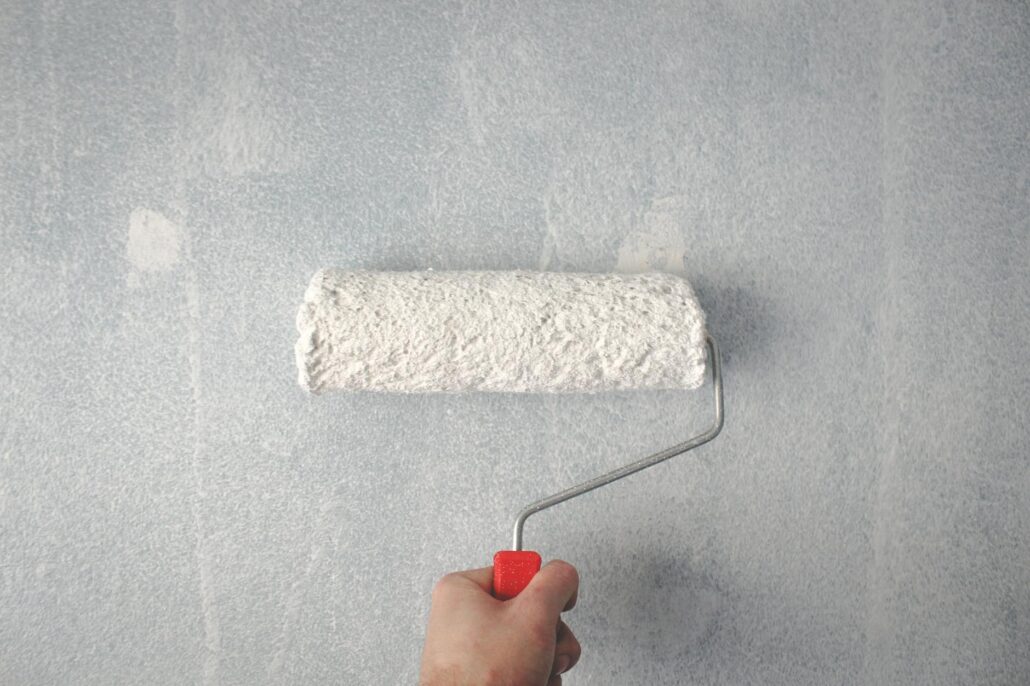 person holding paint roller on wall